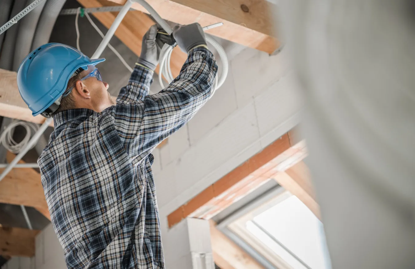 Technician routing network cables through a ceiling