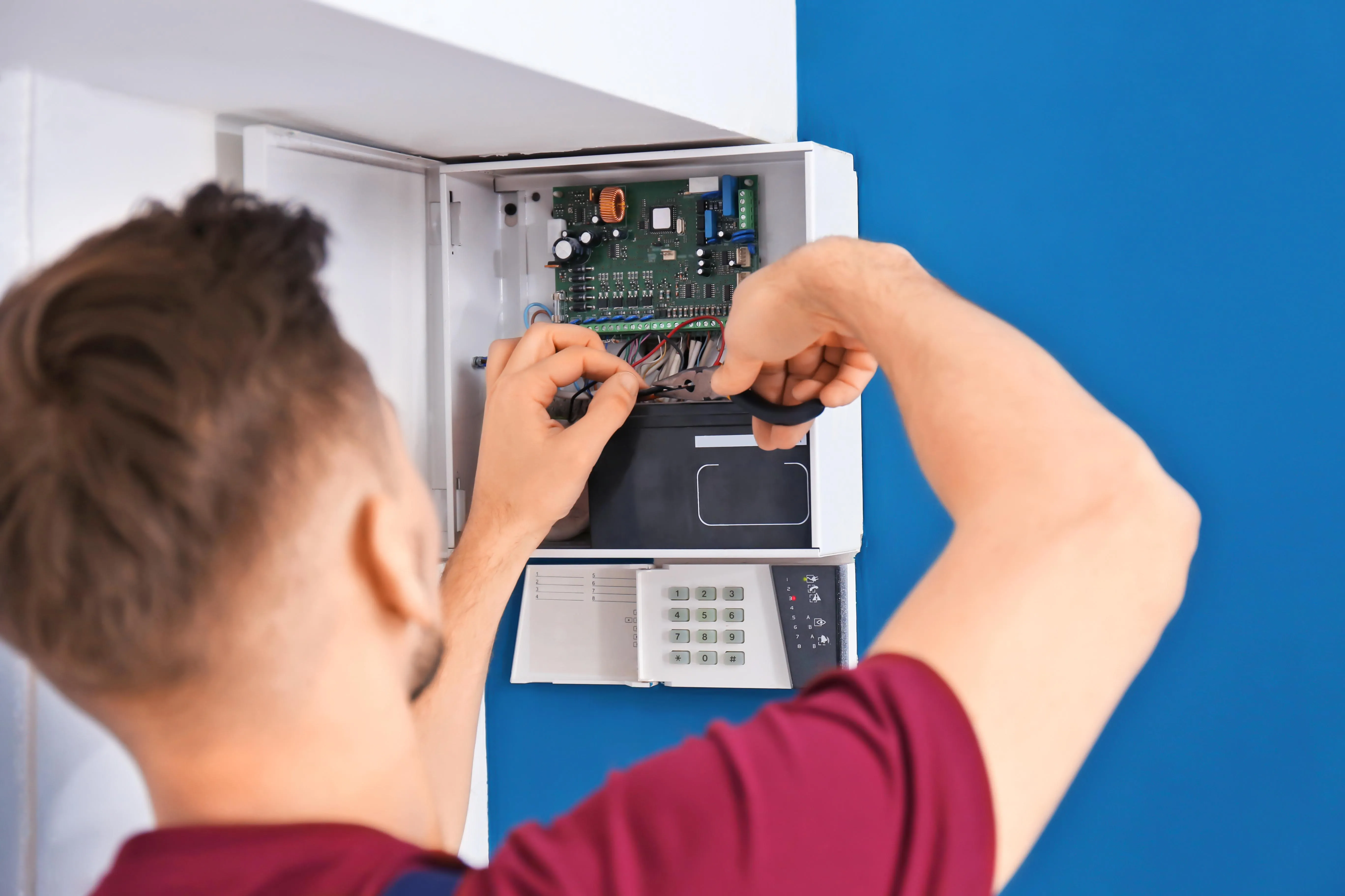 Technician connecting wiring inside an alarm control panel